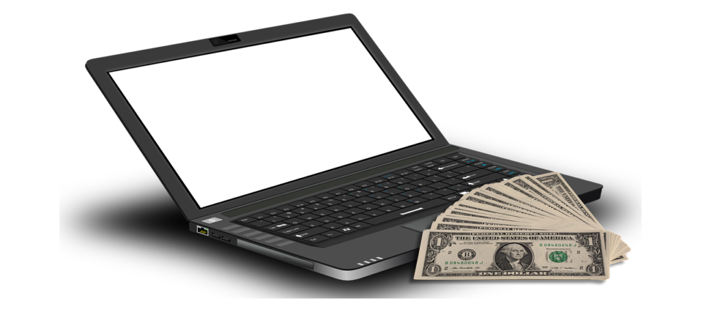 A laptop next to a stack of bills.