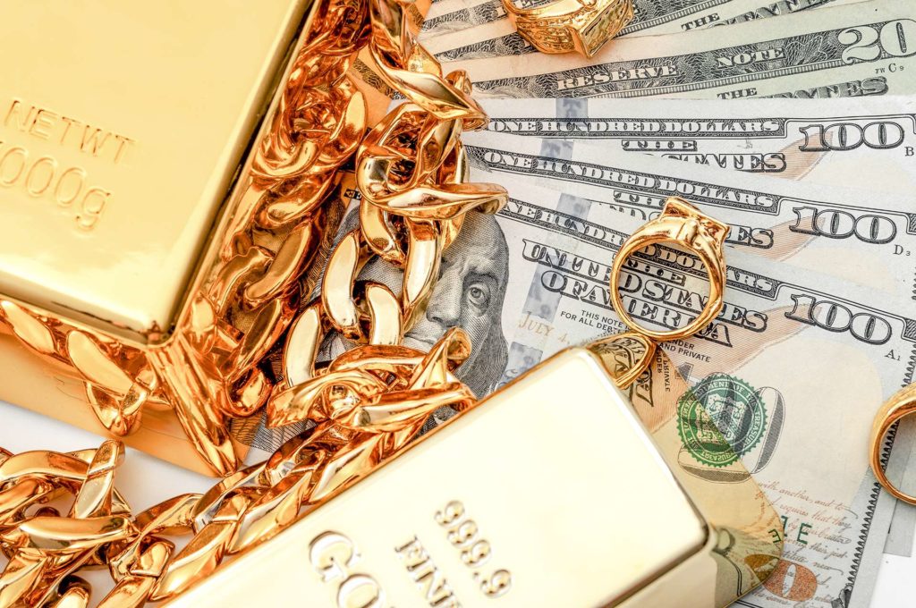 gold bars and jewelry on top of cash