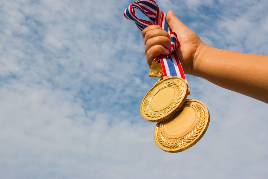  Gewinner Hand angehoben und hält zwei Goldmedaillen
