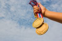 vítěz ruku zvedl a drží dvě zlaté medaile