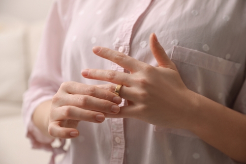 woman removes gold wedding ring from hand