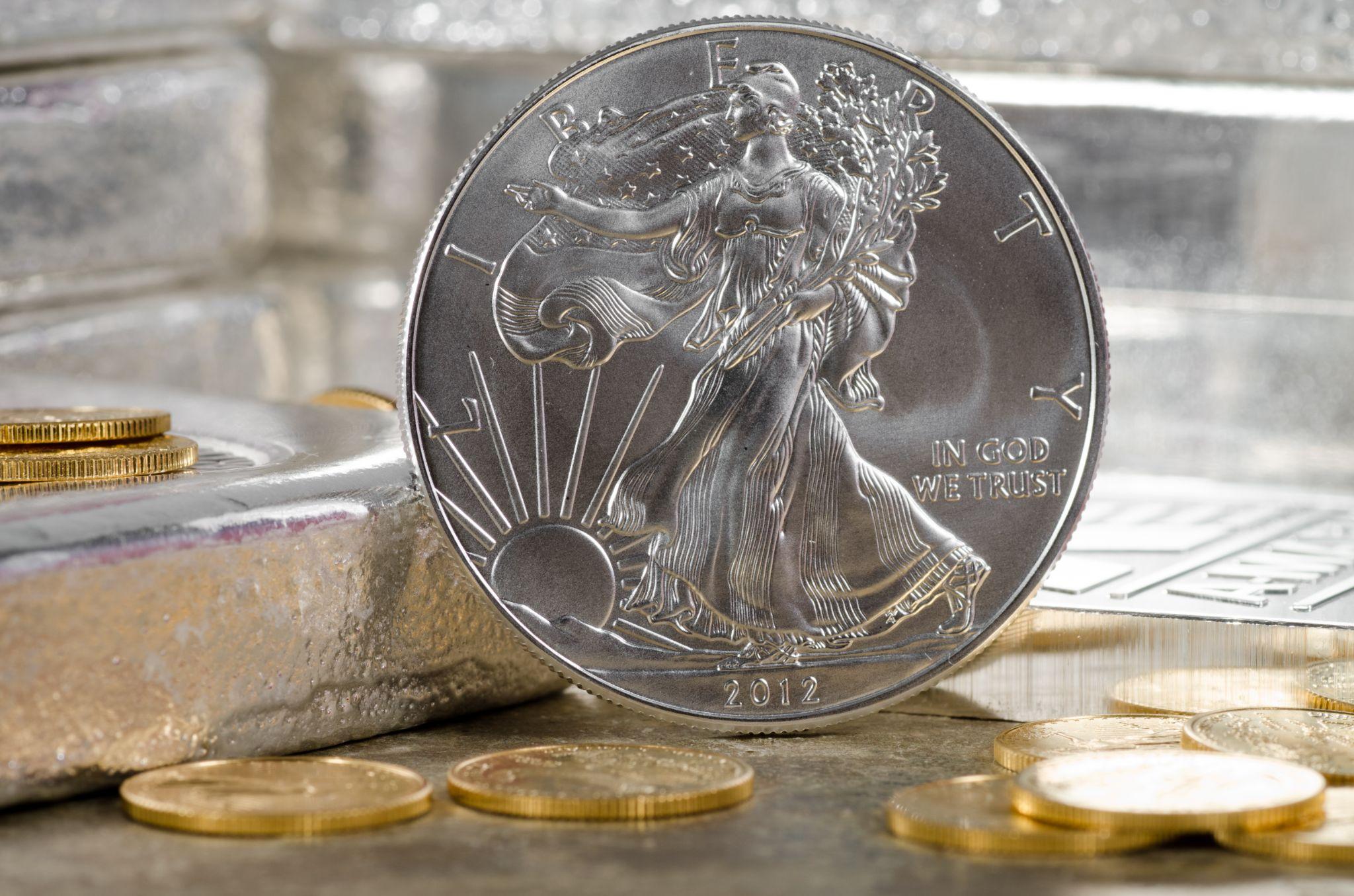 2012 Silver Liberty coin on table with gold coins.
