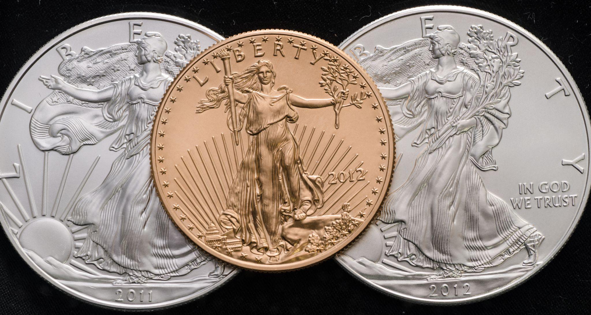 Three liberty coins. Two silver 2012 coins in the background and one gold 2012 liberty coin in the middle.