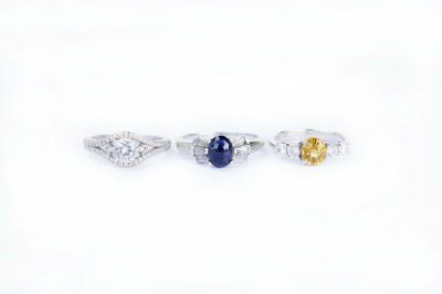 Three diamond rings, one with blue sapphire and one with yellow stone.
